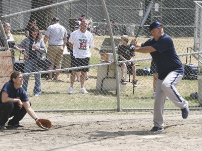 Maple Valley Fire Chief Brad Doerflinger keeps his eye on the ball while Police Chief Michelle Bennett is ready to catch Saturday at Lake Wilderness Park during the 'Gun and Hoses' softball tournament.