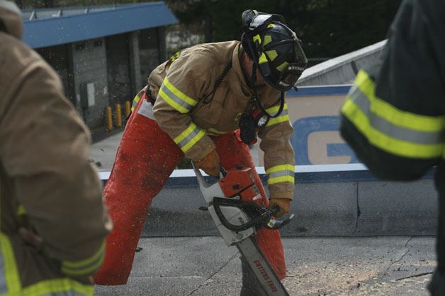 A Maple Valley firefighter uses a chain saw to cut through the top of the roof during a training session. The building