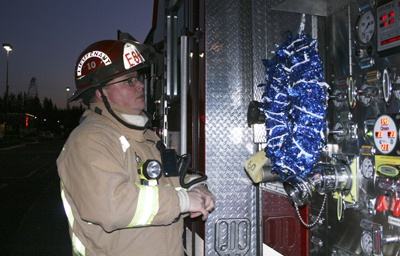 Lt. John Madden from Maple Valley Fire and Life Safety adjusts a wreath on the fire engine in memory of the four slain Lakewood police officers today in front of Papa John's restaurant at Four Corners.