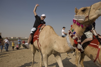 Hydroplane driver Brian Perkins from Black Diamond tries out a camel in Doha