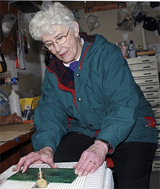 Mary Anderson grinds some stained glass for a project. She helps Oliver Orr teach stained glass art to seniors.