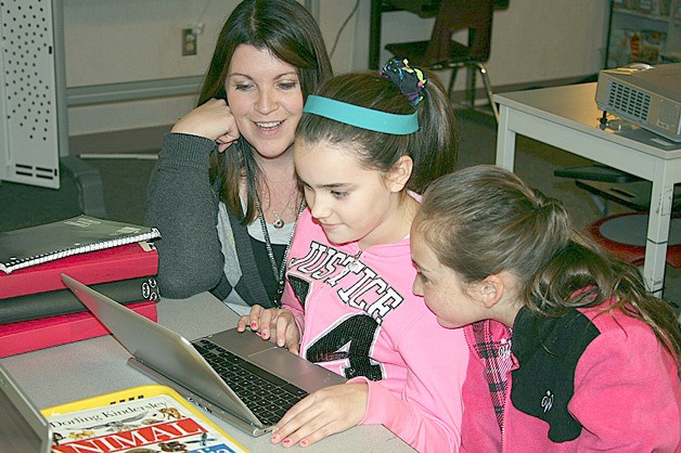 Kennedy and Olivia learn to work their classroom’s new Chromebook with their teacher