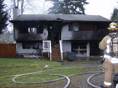 A fire fighter stands outside of a Maple Valley home after it caught fire Monday