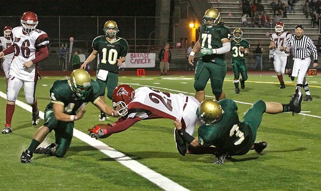 Kentlake's Caleb Mathena stretches as two Auburn defenders try to keep him out of the end zone.