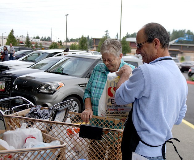 Donna Roetter hands a bag of groceries to Covington Councilman Mark Lanza outside Safeway Saturday during the Mayor’s Day of Concern food drive for the Maple Valley Food Bank.