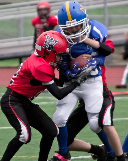 A ball carrier from the 9-11 yeard old Maple Valley Raiders tries to shake off two Sumner Wolfpack defenders in a 2011 game.