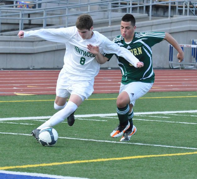 Kentwood’s Hunter Pyne dribbles the ball away from an Auburn defender during a game Monday at French Field. Pyne scored one of Kentwood’s four goals.