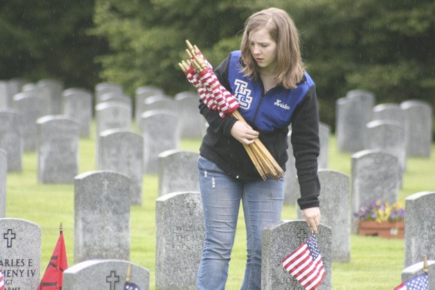 Tahoma Junior High student Kristen Ward places flags in front of graves at Tahoma National Cemetery.