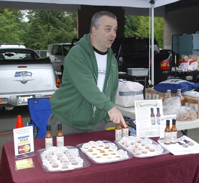 Dennis O’Shields tells a potential customer about his hot sauce at the Maple Valley Farmers Market June 19.
