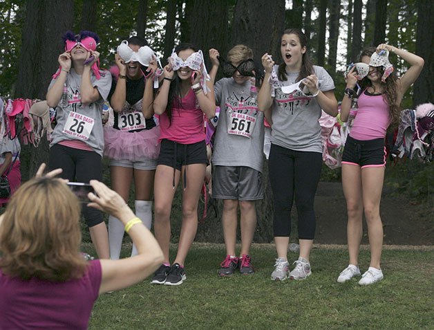 A group of participants in the 2012 Bra Dash 5K at Lake Wilderness park pose in front of the collection of bras prior to hanging theirs on the line.