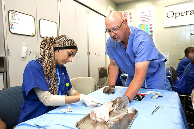 Salma Ramadan of Kent practices suturing techniques on a pig’s foot during the annual MultiCare Nurse Camp while Graham Barr
