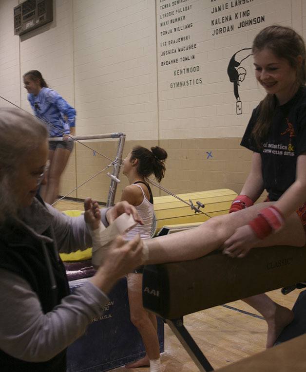 Kentwood senior gymnast Zoe Krambule gets her ankle wrapped before practice on Friday