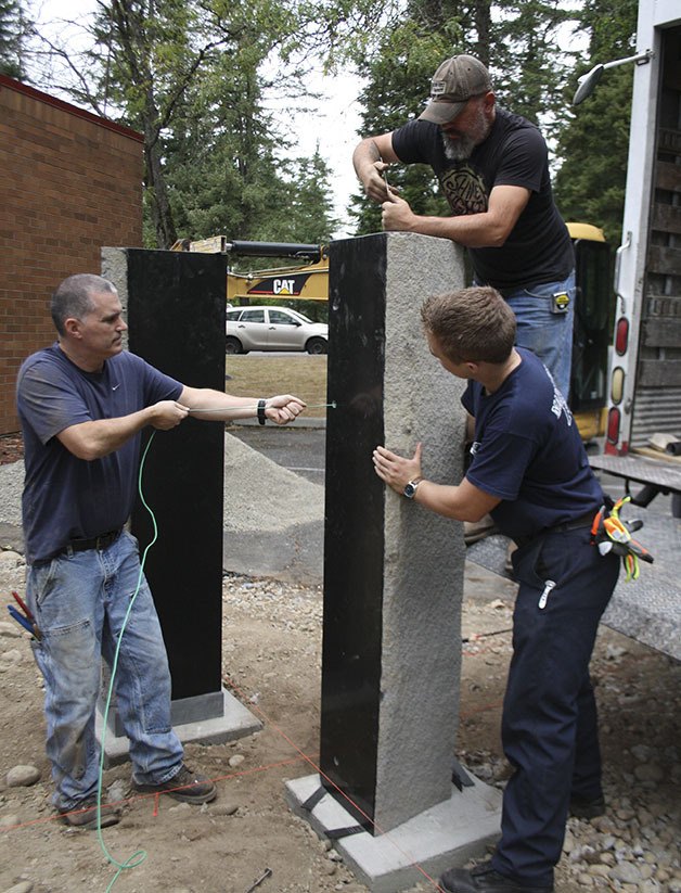 Maple Valley Fire and Life Safety firefighters Kelley Jensen and Tyler Gage along with sculptor Matt Marinelli work to place two columns representing the Twin Towers. The columns are part of a 9/11 memorial that sits outside Maple Valley station 81.