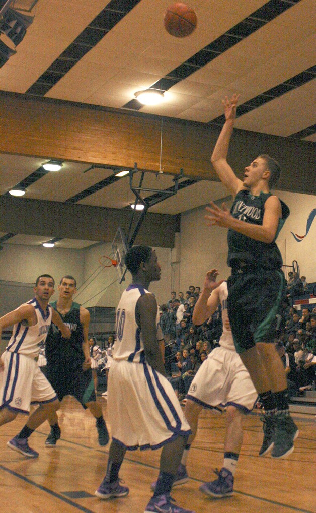 Kentwood’s Austin Benson puts up a shot over Garfield’s Demario Hall in a state regional game Feb. 25.