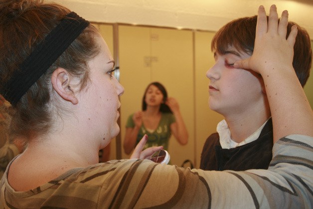 Former Kentwood student and assistant director Cassie Burn-Frederick applies face paint to Shaun Fisher