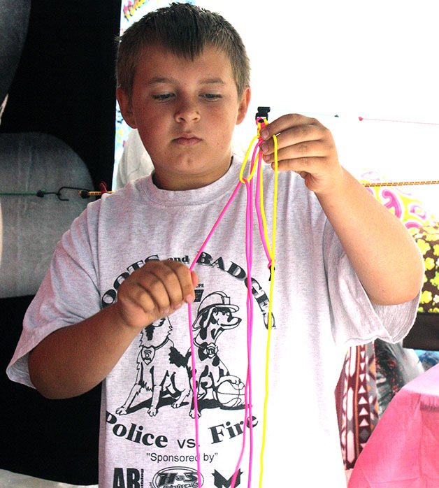 Garrett McGann turned his summer hobby into a business with a booth at the Black Diamond Farmers Market July 12. McGann learned to make survivor bracelets on YouTube after seeing his friend make them. McGann had a display of premade bracelets and was also taking special orders for specific color combinations.