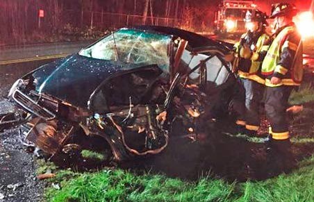 Firefighters check the Honda Civic involved in a head-on collision Monday night in Kent. The woman driver of the Civic died at the scene.