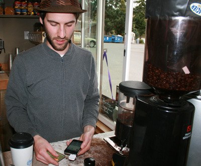 Levi Anderson swipes a credit card through the Square device attached to his iPhone inside of his coffee stand.