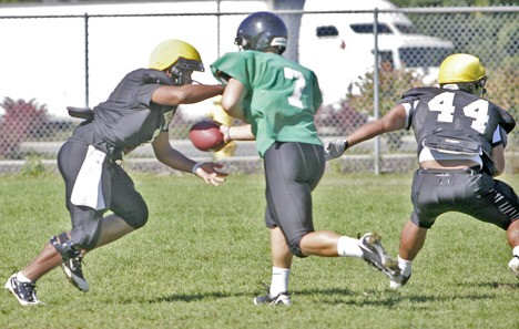 Kentwood running back Joseph Banks takes a hand off from quarterback Shane Green and charges to the line during practice  Aug. 25