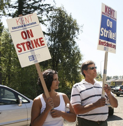 Marla Boyd and Karl Weir-Haug waves signs at cars passing by near Kentlake High School Thursday during the first day of the Kent Education Association strike.