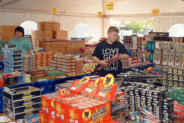 Alex Nelson rearranges a display of fireworks at the Black Cat stand in the Four Corners Safeway parking lot.