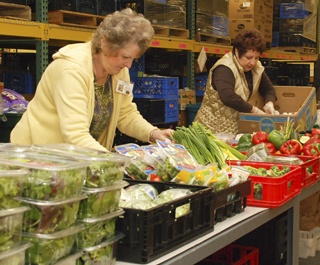 Volunteers Yvonne Janssen and Joanie Hains sort through donated items at the Maple Valley Food Bank on Monday.