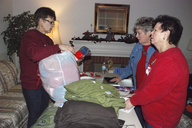 Casey Rust explains to Jamie Redick of Maple Valley and Ida Tribble of Auburn which items should be wrapped together during a work party Dec. 20.