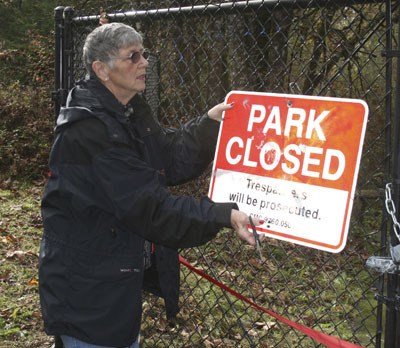 Mayor Margaret Harto takes down the park closed sign during the Jenkins Creek Park reopening celebration Saturday.