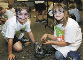 Matthew Wiernals and Megan Philips (left) took apart a radio Wednesday to create a fantasy invention tied to comic book superheroes during Camp Invention. The five-day event this week at St. John the Baptist Church in Covington