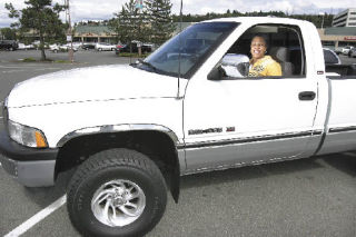 Kelly Carroll smiles from behind the steering wheel of a pickup truck donated by a Tacoma automobile dealer to R. Place for Refuge. The charity