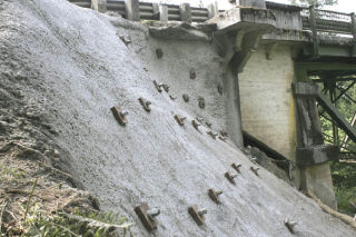 This was the week for a crumbling hillside beside State Route 169 near Black Diamond to undergo emergency repairs by the state Department of Transportation (DOT). Workers impaled the slope with soil nails (above) and then sprayed it with concrete (left). If the hillside hadn’t been stabilized