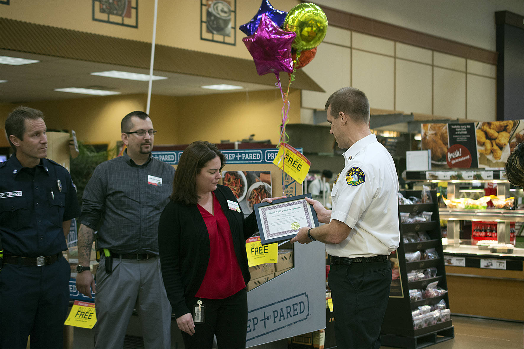 Fire Chief Aaron Tyerman hands the Maple Valley Fred Meyer store manager a framed certificate to thank the Fred Meyer employees for their assistance during an incident at their store. Photo by Kayse Angel