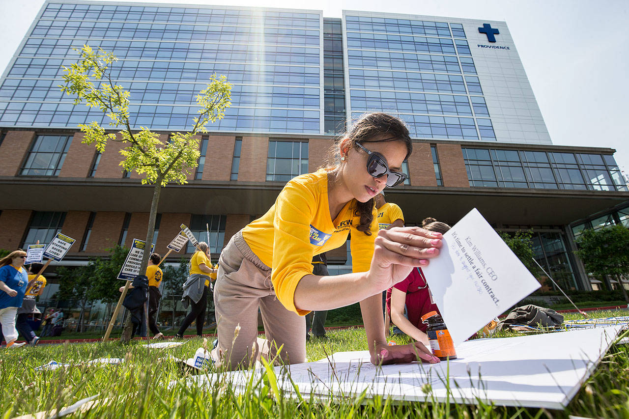 UFCW organizer Graciela Nune affixes cards addressed to various administrators on a board as nurses with UFCW 21 and their supporters picket at Providence Regional Medical Center Everett on Wednesday. The boards, with notes pleading for a contract settlement, are to be presented to the administrators tomorrow. (Andy Bronson / The Herald)