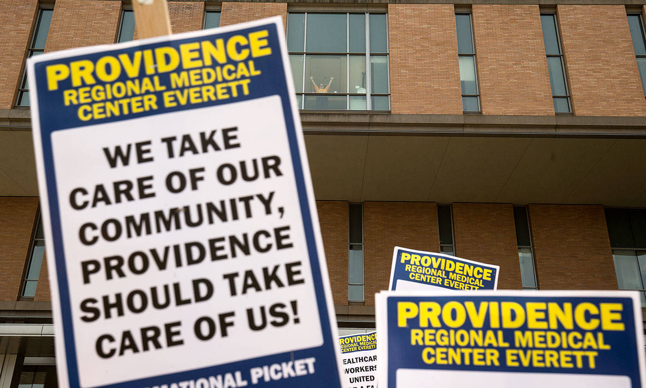A supporter waves from a window as nurses with UFCW 21 and their supporters picket outside Providence Regional Medical Center Everett on Wednesday. (Andy Bronson / The Herald)