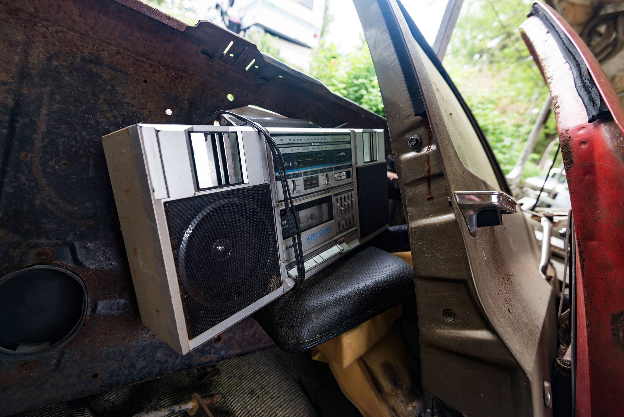 A boombox, in relatively good condition, is found wedged between the bare interior of a bus and two separated car doors. Photo by Caean Couto