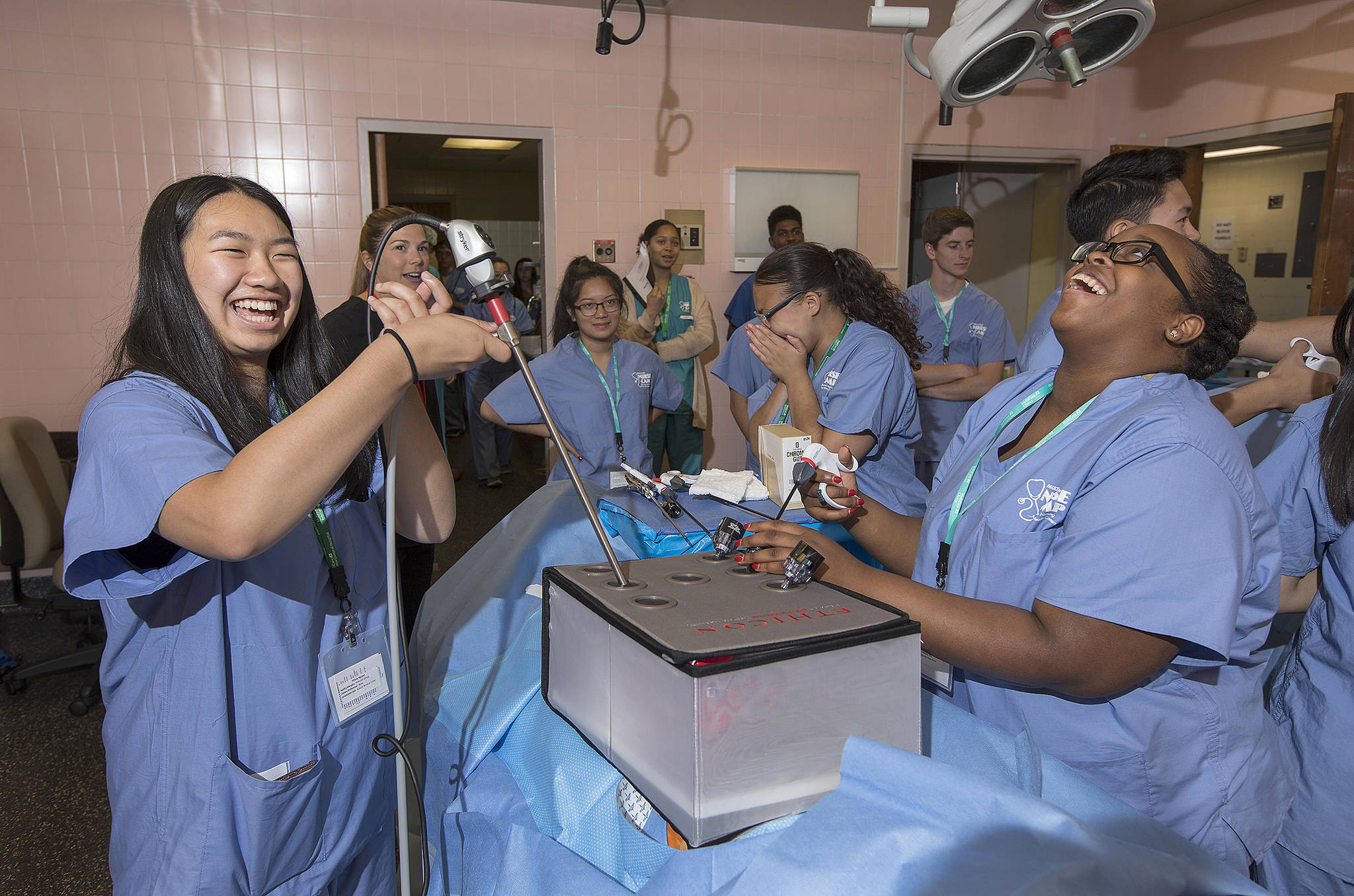 Tiffany Nguyen, 17, left, of Kent, laughs with Tiffany Jinks, 16, of Tacoma, as she attempts to grab candy with an alligator clamp while learning about laparoscopic surgery last week during Nurse Camp at Tacoma General Hospital. Photo by Patrick Hagerty