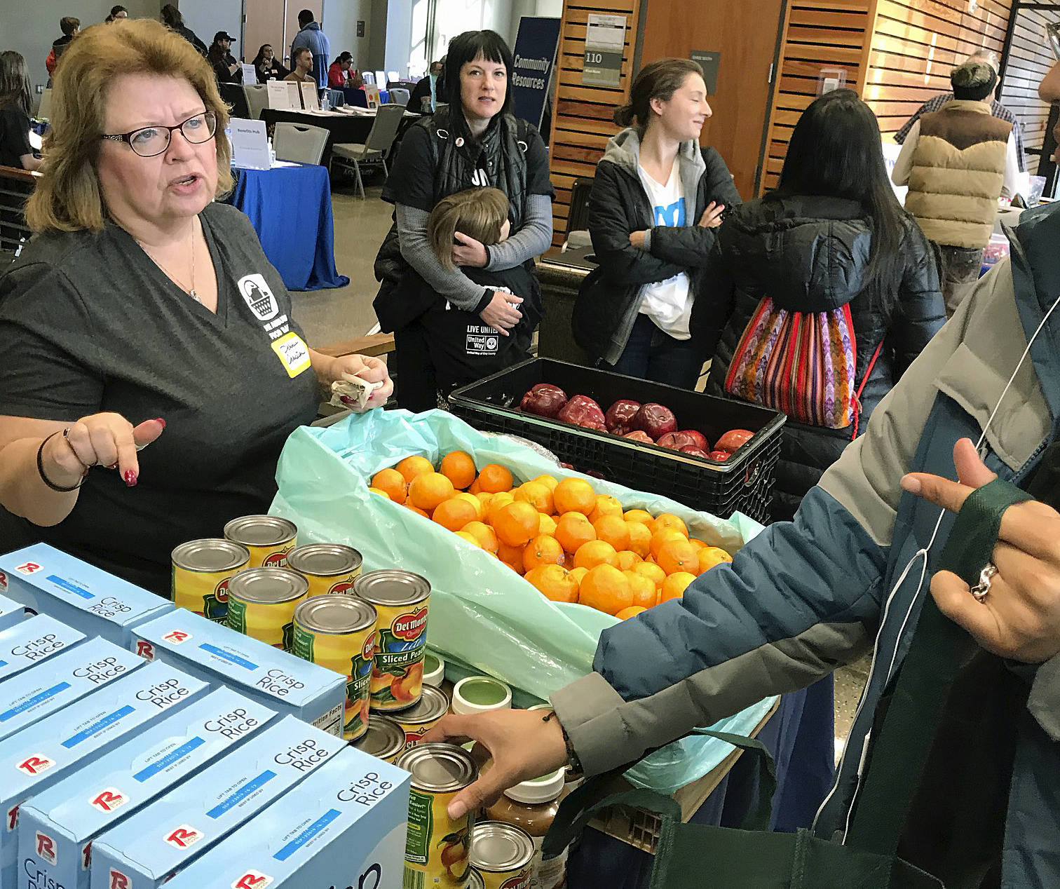 Debbie Christian, executive director of the Auburn Food Bank, distributes fruit and other offerings to families during the United Way of King County’s Family Resource Exchange at Green River College last Saturday.