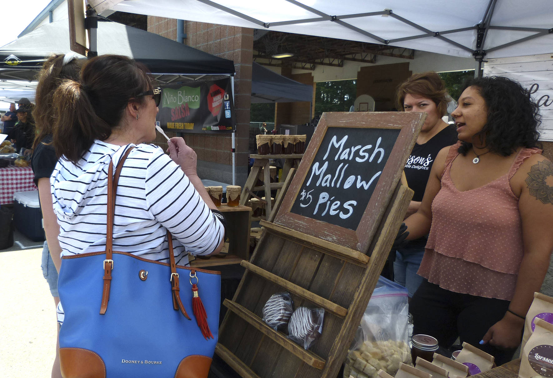 Community members takes samples at one of the stands at the Maple Valley Farmers Market.