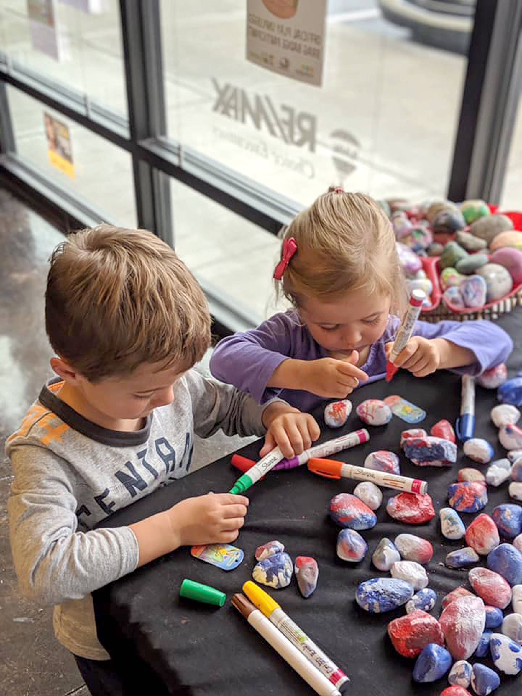 Photo courtesy of the Covington Chamber of Commerce.                                 Two children color rocks to earn a “Brag Badge” from Covington’s Play Unplugged summer campaign.