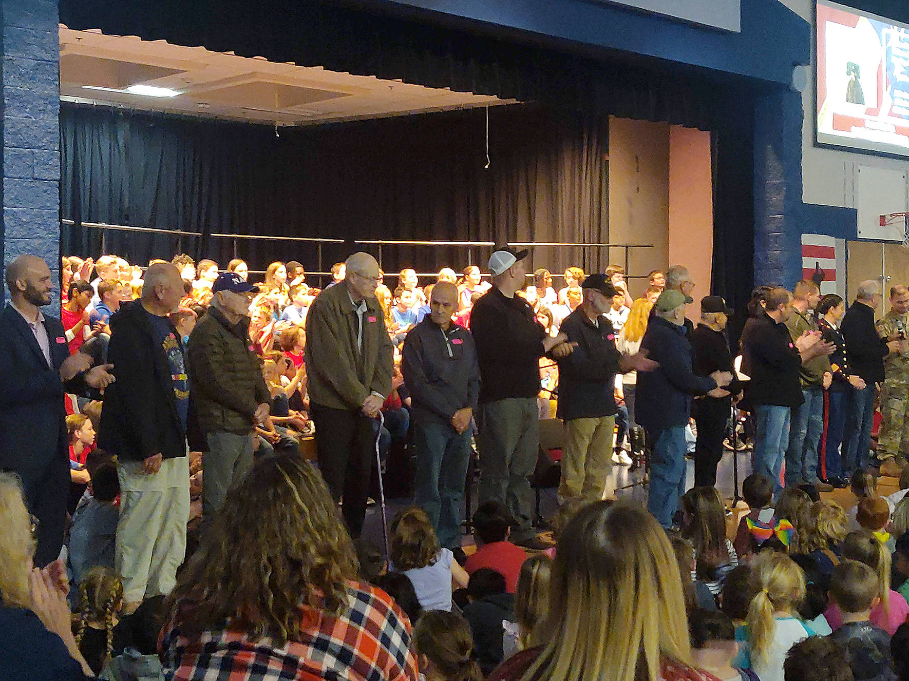 Veterans in the crowd were asked to stand near the stage during a special Veterans Day Assembly. Veterans introduced themselves, said where they served and for what military branch, and were given roses as a “thank you” for their service by the Glacier Park Elementary School fifth grade class. Photo by Danielle Chastaine.                                 Veterans in the crowd were asked to stand near the stage during a special Veterans Day Assembly. Veterans introduced themselves, said where they served and for what military branch, and were given roses as a “thank you” for their service by the Glacier Park Elementary School fifth grade class. Photo by Danielle Chastaine.