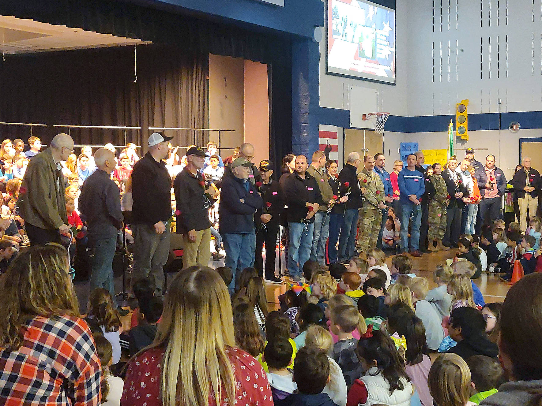 Veterans in the crowd were asked to stand near the stage during a special Veterans Day Assembly. Veterans introduced themselves, said where they served and for what military branch, and were given roses as a “thank you” for their service by the Glacier Park Elementary School fifth grade class. Photo by Danielle Chastaine.                                 Veterans in the crowd were asked to stand near the stage during a special Veterans Day Assembly. Veterans introduced themselves, said where they served and for what military branch, and were given roses as a “thank you” for their service by the Glacier Park Elementary School fifth grade class. Photo by Danielle Chastaine.