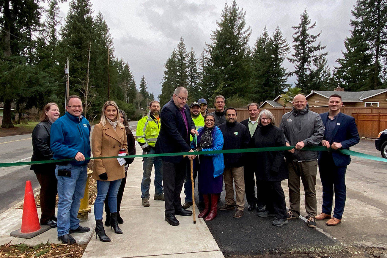 Covington Mayor Jeff Wagner cuts the ribbon on the completed 164th Avenue Southeast Pedestrian Improvement Project on Thursday, Jan. 9, surrounded by city officials.                                Photo courtesy of the City of Covington.