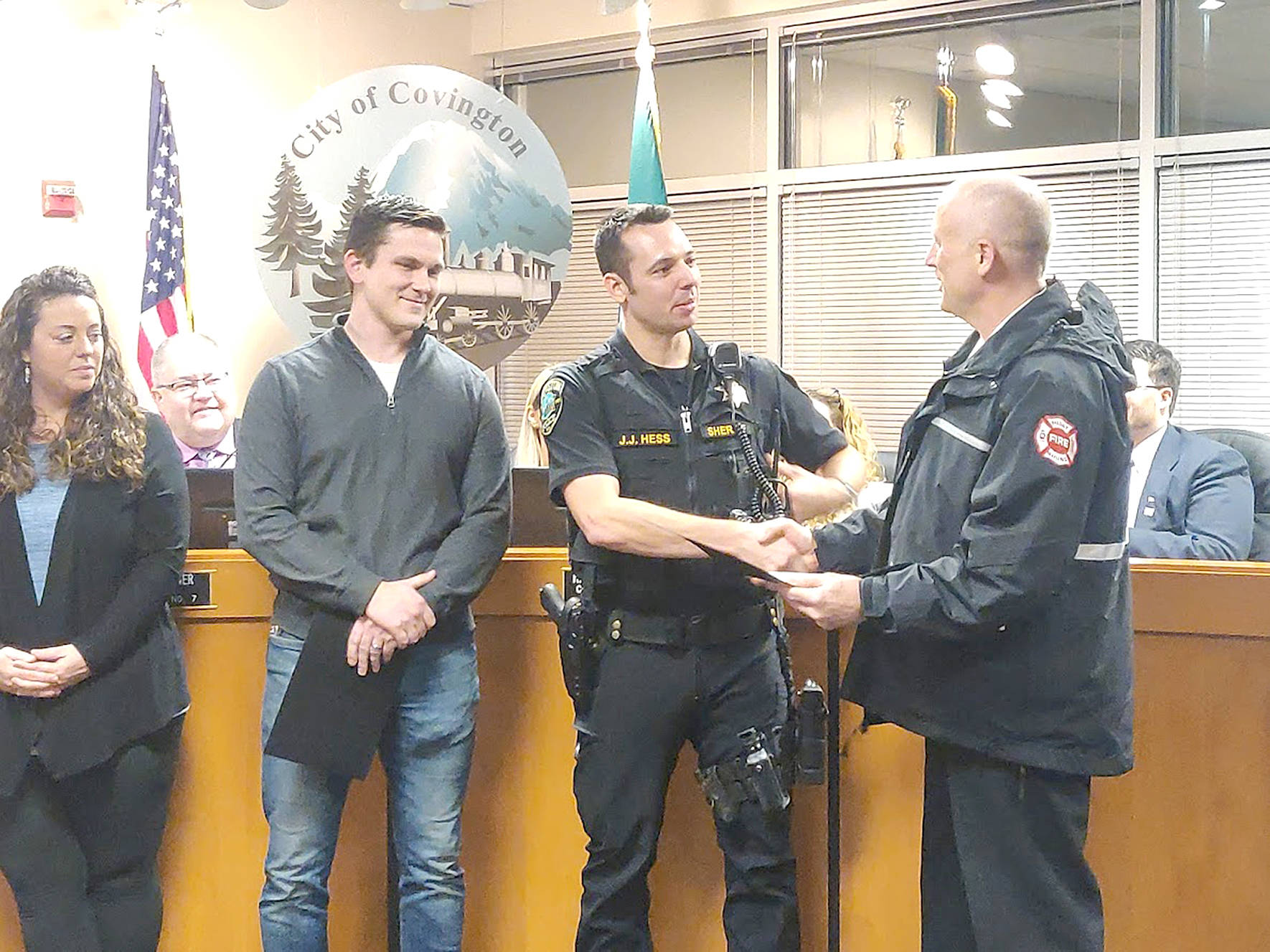 Covington Police officers Branson Carr, left, and Jordan Hess, right, were honored by Captain Joe Root of the Puget Sound Regional Fire Authority for their efforts in saving resident Debra Stevens life during the Monday, Jan. 27, 2020, city council meeting. Photo by Danielle Chastaine.