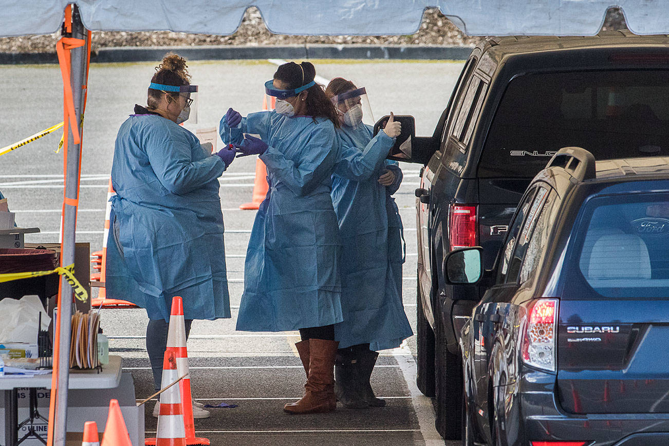 One medical worker gives a thumbs up as two others collect a swab after a test for the COVID-19 virus at a drive-thru testing site, March 23, 2020 in Everett. Andy Bronson / Everett Herald