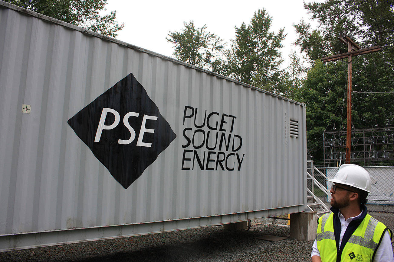 In this 2019 file photo, Puget Sound Energy product development manager John Dooley stands in front of one of four units at the Glacier Battery Storage Project in northwest Washington state. The project can provide power to the small town of Glacier for around two hours if needed. (Sound Publishing file photo)