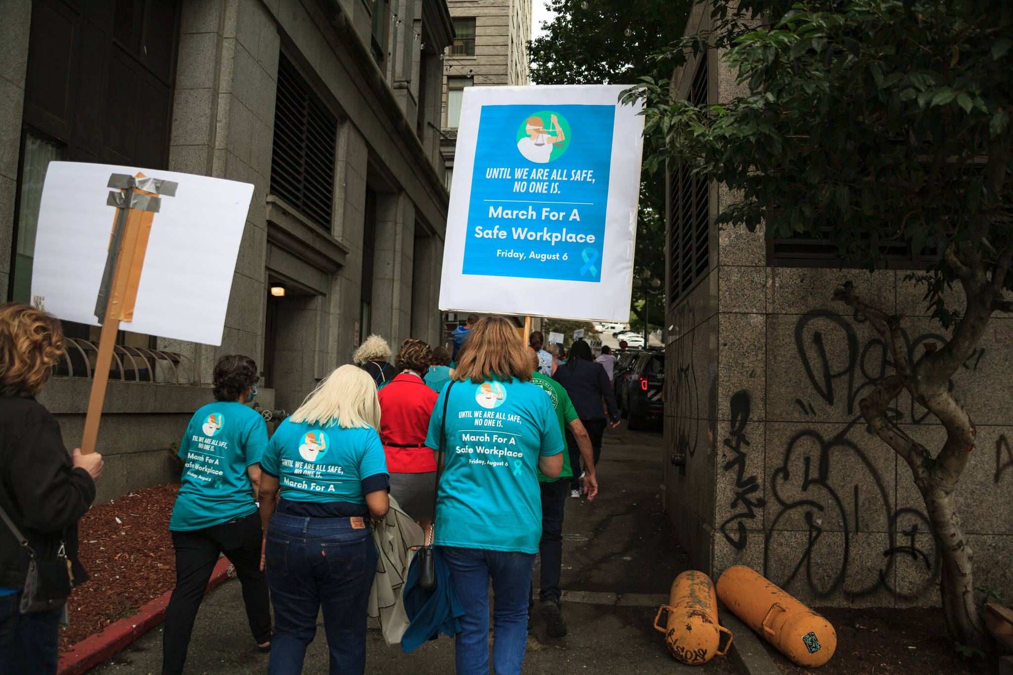 County employees and supporters walk past the King County Courthouse during a march for women’s safety at work in Seattle on Friday, Aug. 6, 2021. The march was scheduled after a woman was attacked in a bathroom at the King County Courthouse. Photo by Henry Stewart-Wood/Sound Publishing