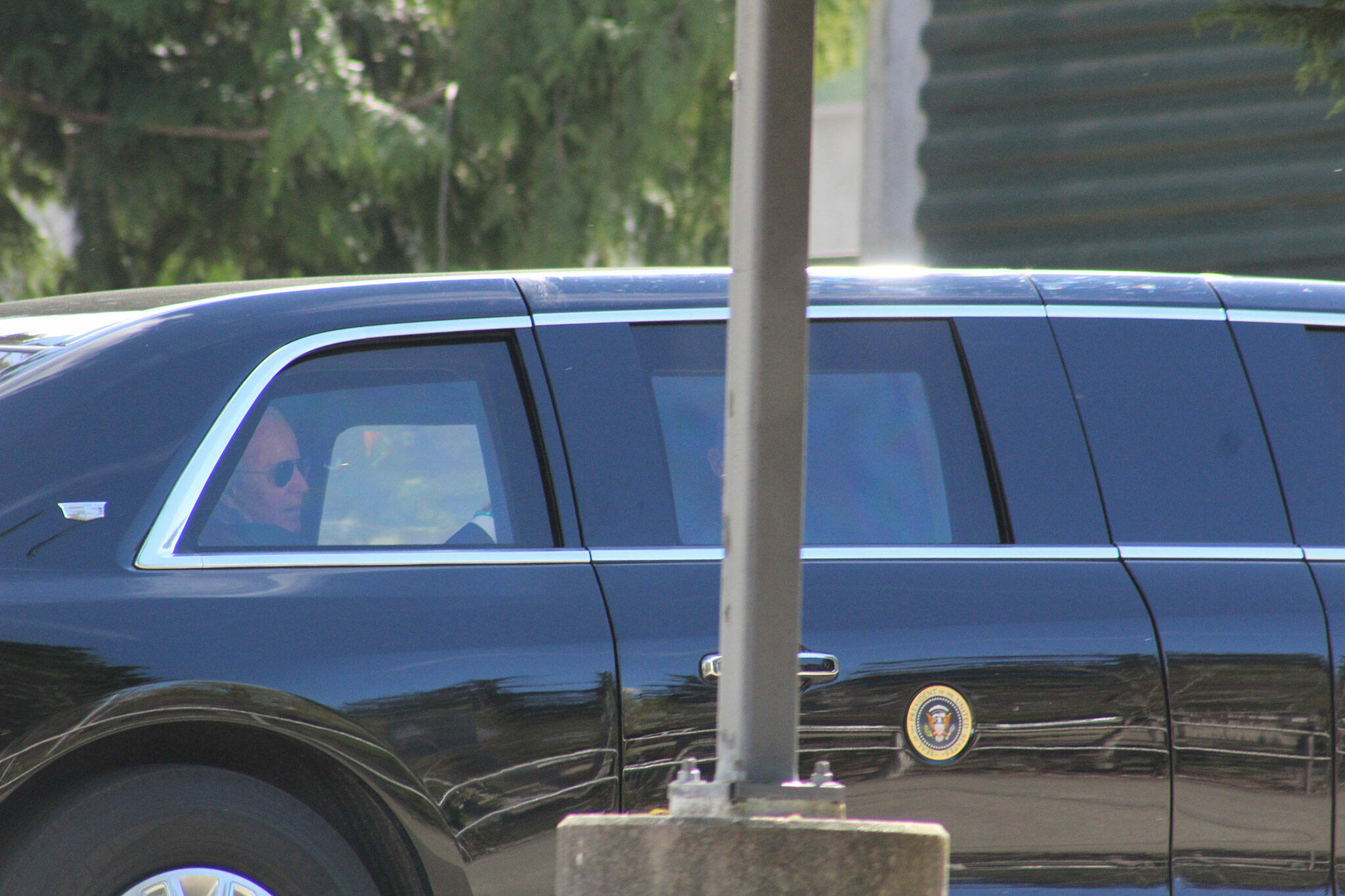 A man who appears to be President Joe Biden is seen in the back seat of a car in the president’s motorcade, departing the Green River College after the president’s speech. Photo by Alex Bruell/Sound Publishing