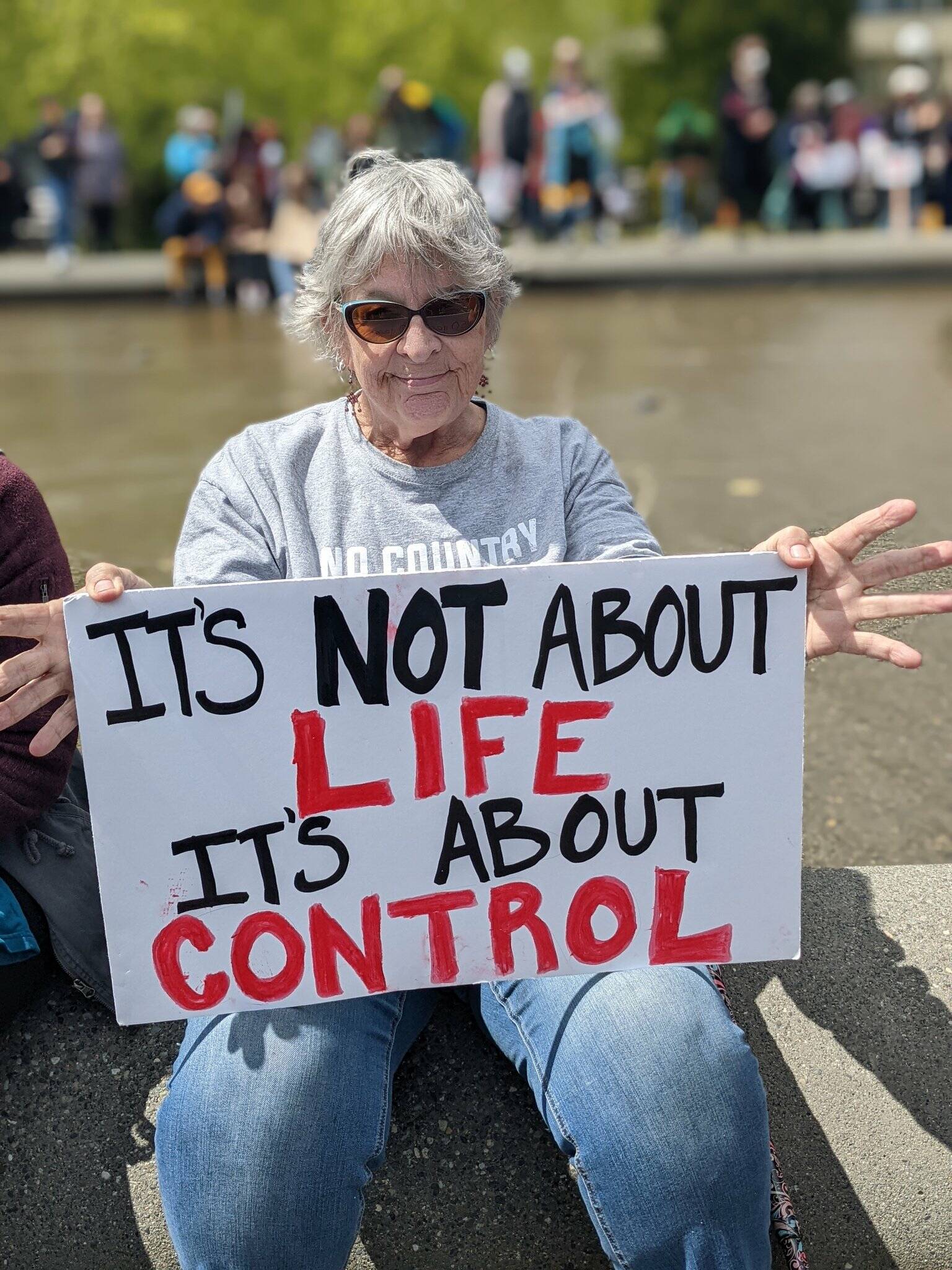 A woman sits with a sign at the reproductive rights protest on May 14, 2022, at Cal Anderson Park. Hannah Saunders/Sound Publishing