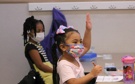 A kindergarten student at Panther Lake Elementary raises her hand during attendance on the first day of in-person learning on March 15, 2021. The DOH updated guidance that students and staff who return from isolation must wear masks in school for five days. Photo by Olivia Sullivan/Sound Publishing