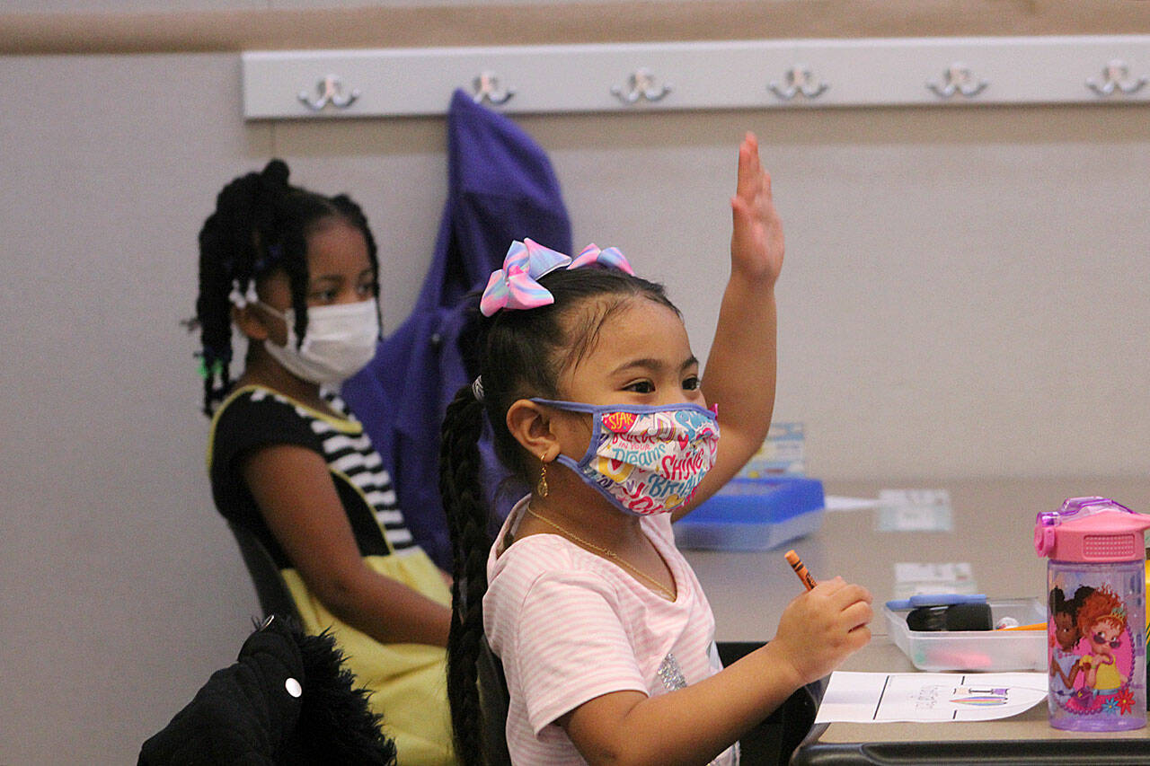 A kindergarten student at Panther Lake Elementary raises her hand during attendance on the first day of in-person learning on March 15, 2021. The DOH updated guidance that students and staff who return from isolation must wear masks in school for five days. Photo by Olivia Sullivan/Sound Publishing